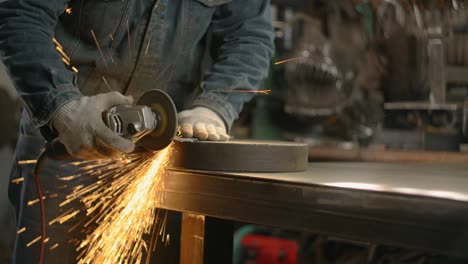 locksmith sands the edges of a metal detail by electric grinder with a lot of sparks in slow motion, metalwork at workshop, 4k 60p prores hq