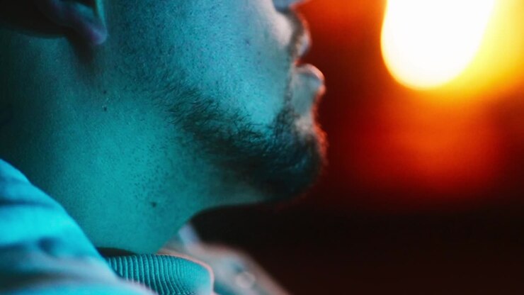 Close-up de homem movendo a cabeça com luz laranja ao fundo