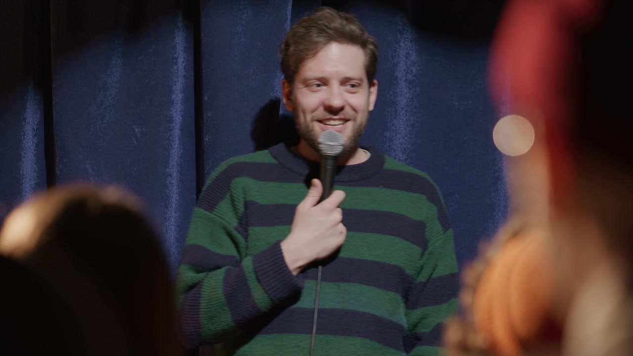 Giovane uomo in piedi sul palco che racconta barzellette durante un'esibizione di stand-up