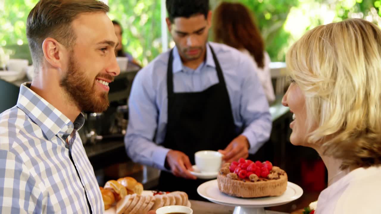 Male owner serving coffee to customers