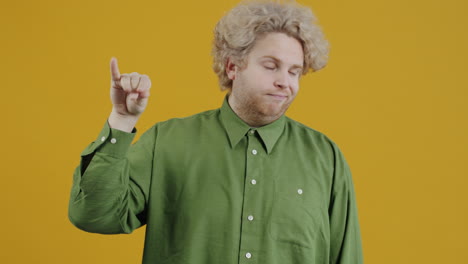 man with curly hair making dismissive gesture