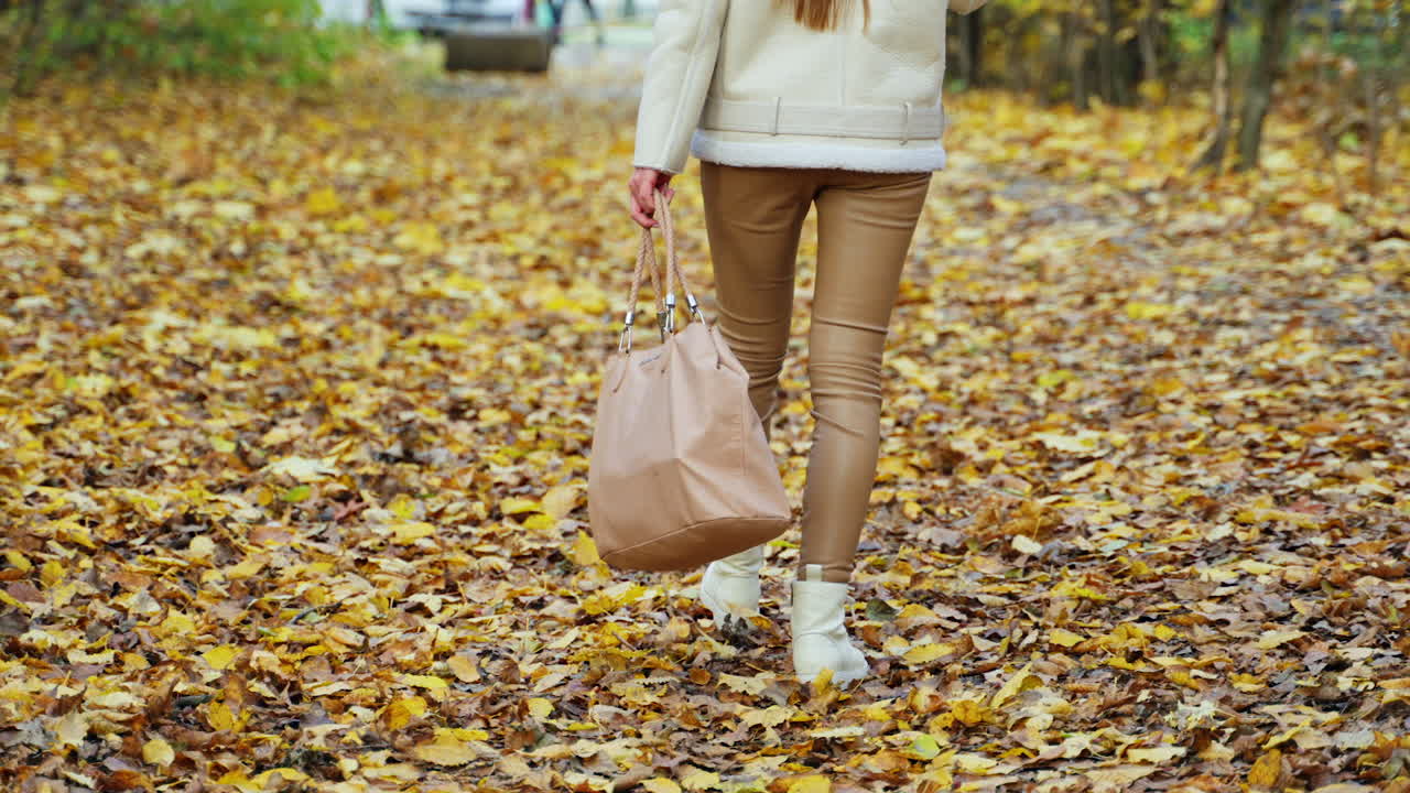 Donna che cammina tra le foglie d'autunno