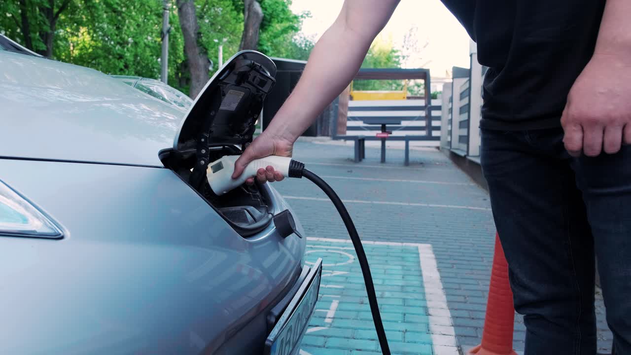 Bir elektrikli arabanın yakıt ikmal işlemi. Elektrikli eco arabanın şarj olduğu kapağın altından bir çekim. Elektrikli araba şarj kapağı otomatik olarak açılıyor. Bir erkek eli bir elektrikli araba takıyor