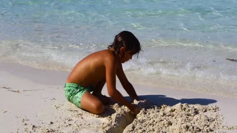 A-young-Caucasian-boy-is-digging-in-sand-on-Cocoplum-Beach-on-Exuma-in-the-Bahamas