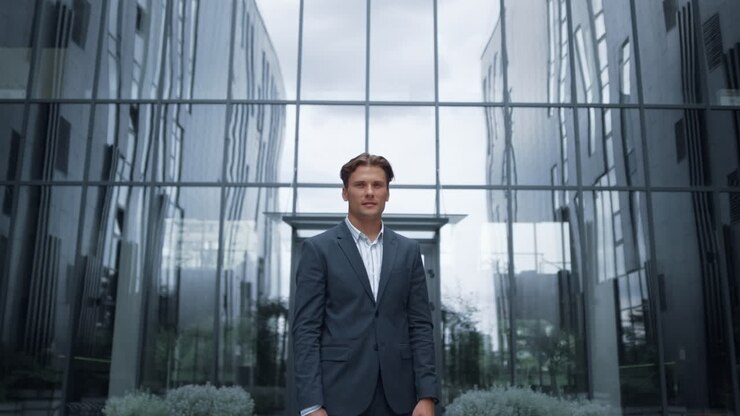 Portrait businessman posing at modern glass office building alone.