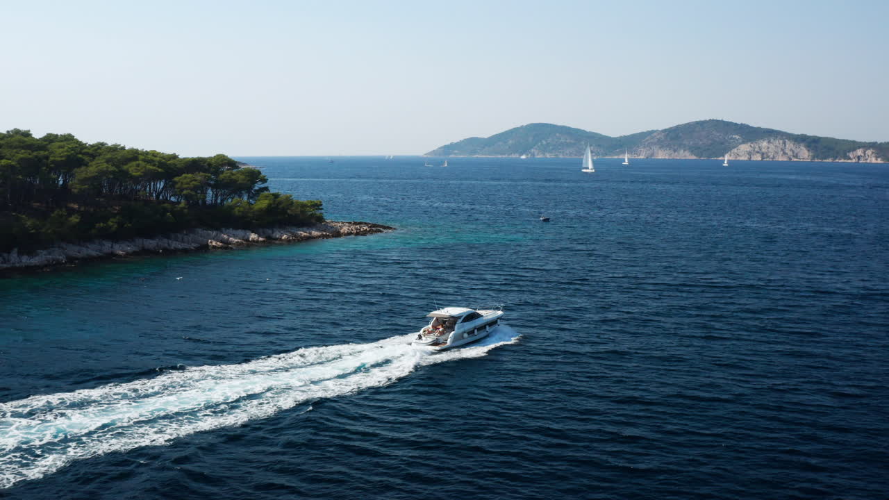 Motoscafo con turisti che solca il mare azzurro, lasciando una scia, in estate nelle Isole Paklinski, Hvar, Croazia.