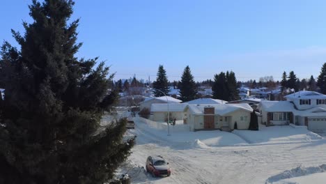 aerial reveal panout of snow covered winter town of low rise quant cozy white bed in breakfast dettached homes brick rectangular chimney and snowed in roads cars paths with tall fraser fir trees 2-2