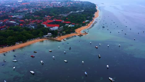 seashore dotted with fishing boats at sanur town and resort in bali island, indonesia