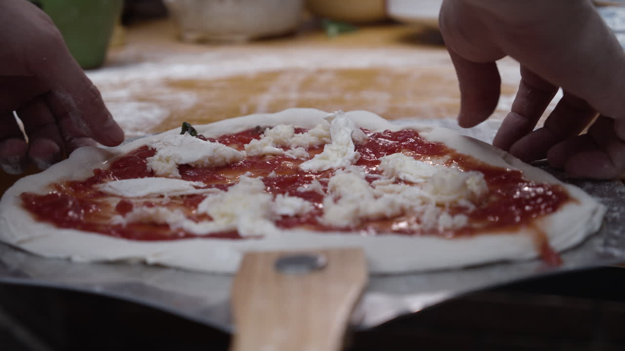 Chef slides the pizza dough onto the tray and stretches it to from a circle