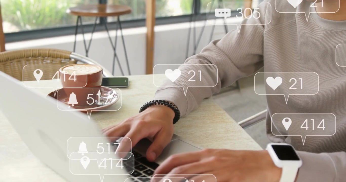 Man tapping pad at cafe, causing social icons around laptop and hands, typing to track engagement