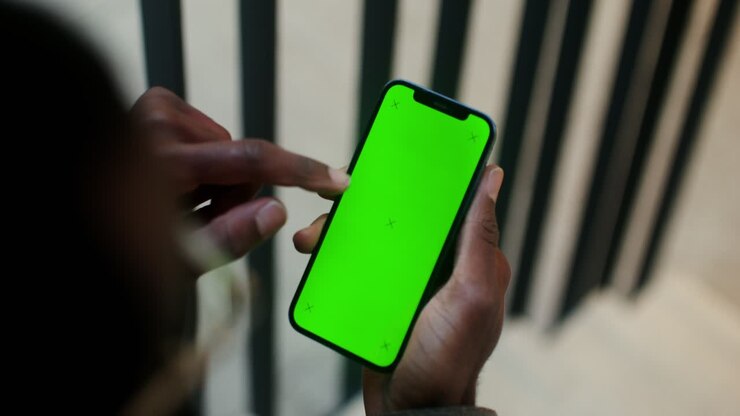 Person holding smartphone with green screen