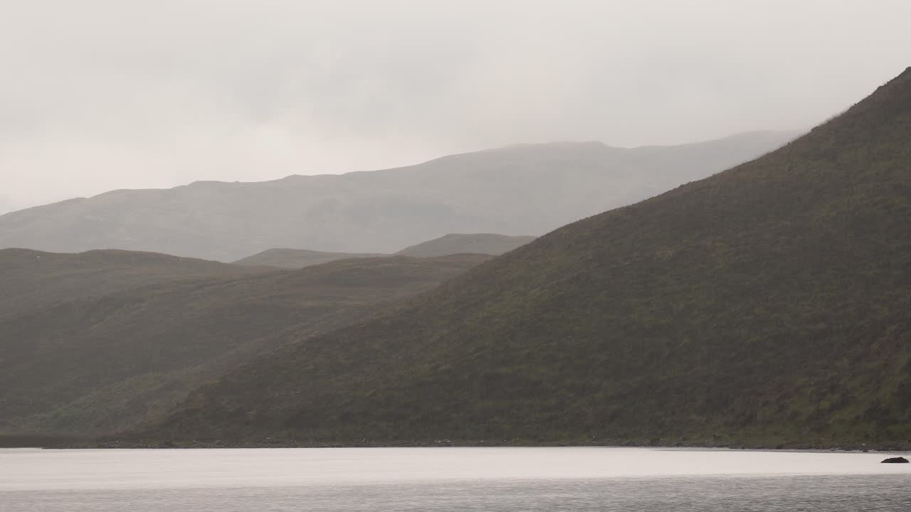 lluvia cayendo sobre las colinas y el lago en un paisaje escocés en la isla de skye