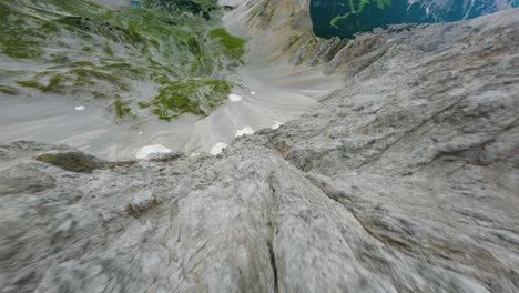 fpv drone dives down a steep rocky wall of an alpine mountain in tyrol region of austria