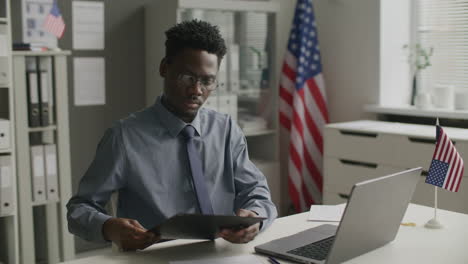 african american visa officer working on laptop at desk in us embassy