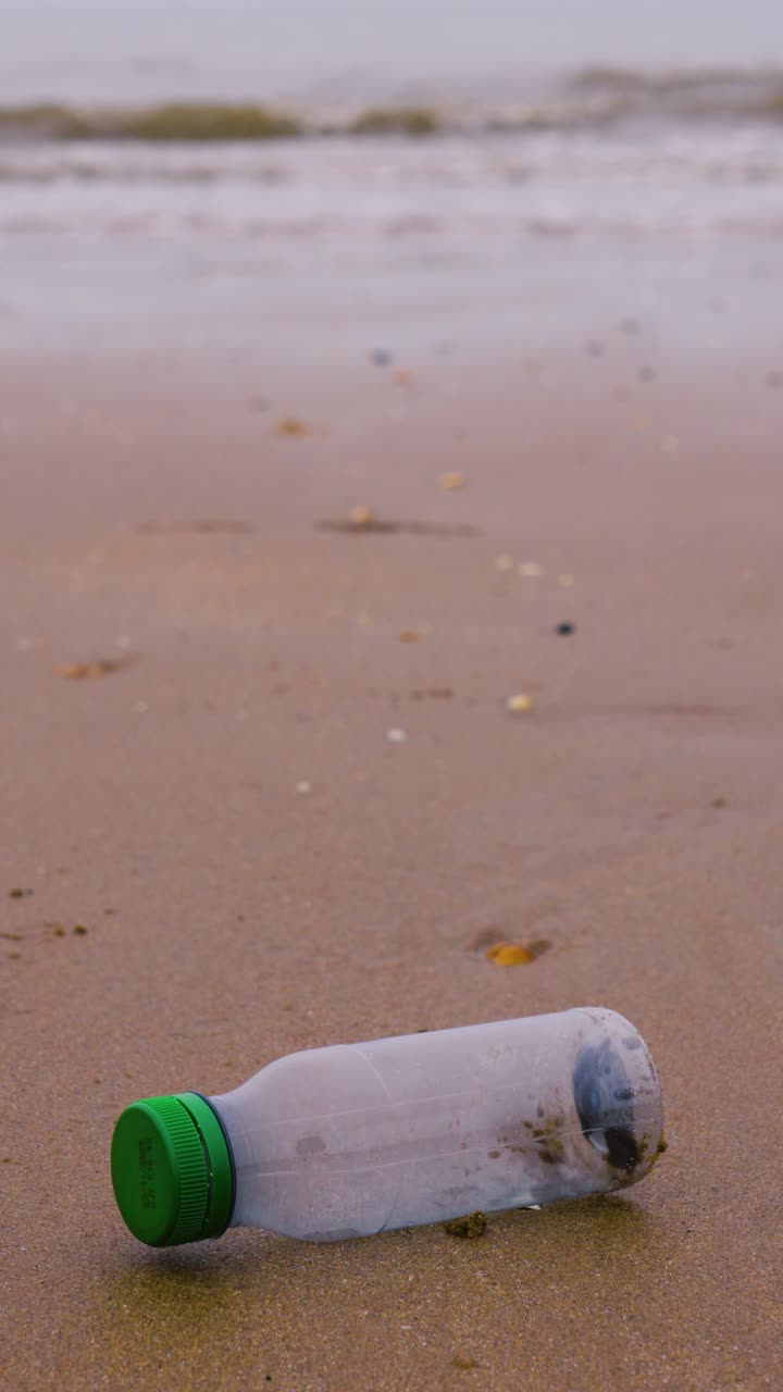 Vertical Video Plastic Bottle on Beach After Being Discarded Creating Pollution of Natural Environment
