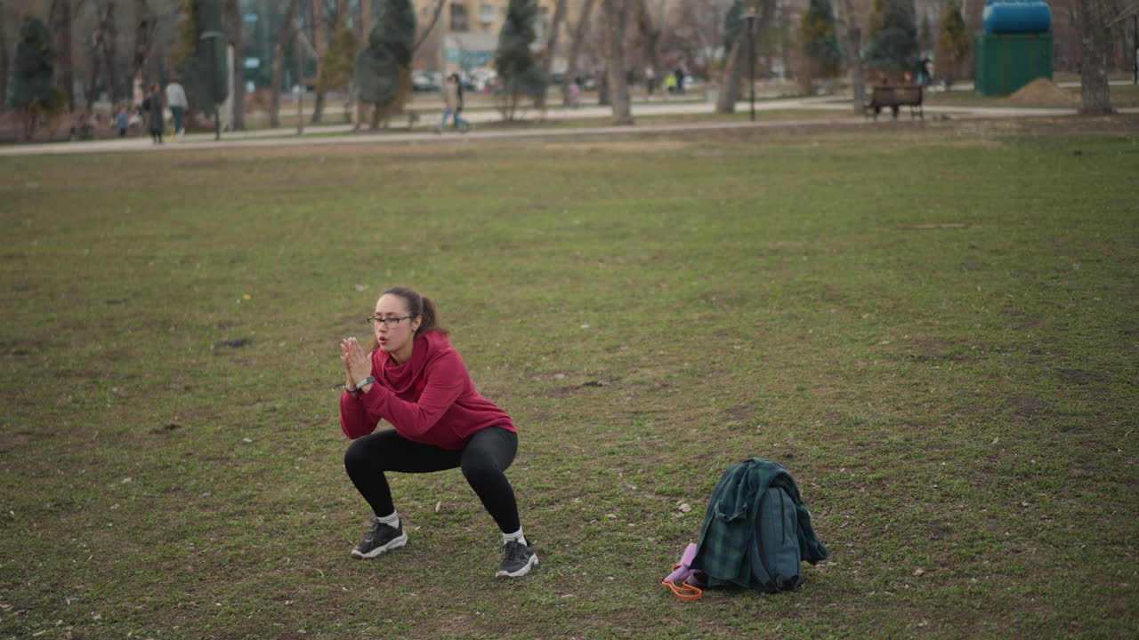 Female Practicing Park Exercises, Young Lady Performing Squat Exercises Outside, An Energetic Young Woman Showcases Various Squat Techniques Using Accessories In City Park Environment