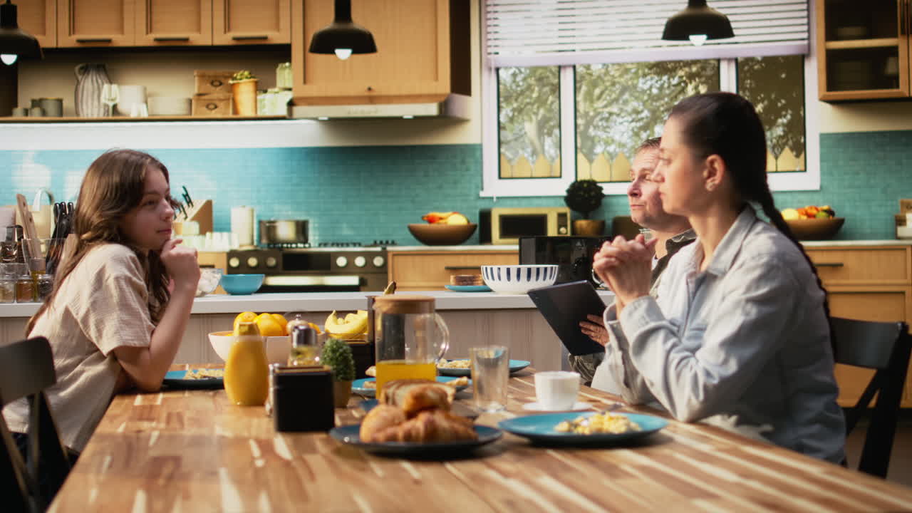 Working dad on tablet ignoring daughter and family at breakfast table