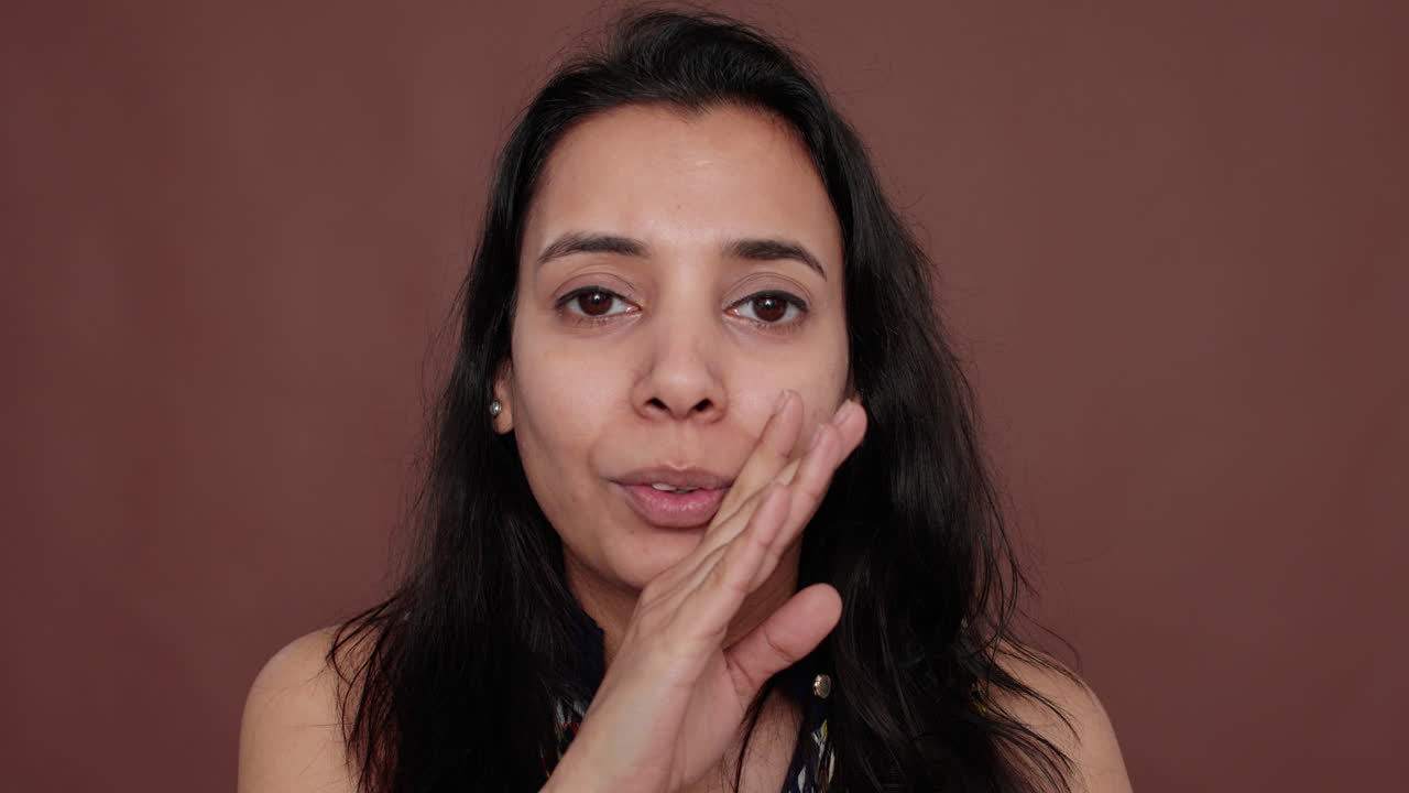 Portrait of indian woman sharing overheard secret in studio
