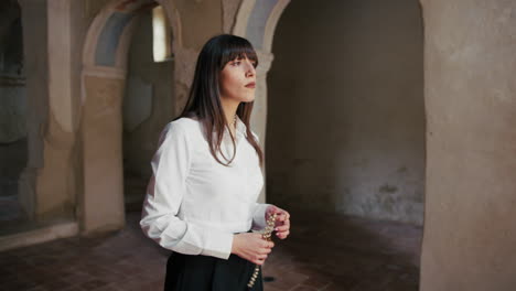 woman holding a rosary in the church standing still and watching up