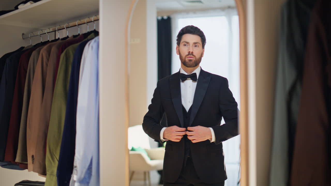 Elegante hombre abrochándose el blazer en el vestidor. Caballero seguro con un aspecto impecable.