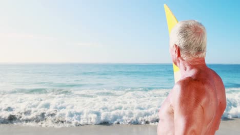 Retired-old-man-holding-surfboard-near-sea