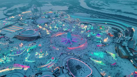 drone shot of the harbin ice festival, china. sculptures, fun rides, and people having a good time during sunset.
