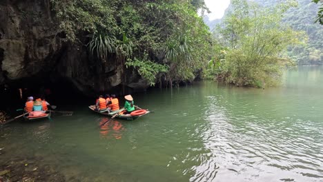 turistas remando botes a través de una tranquila cueva fluvial