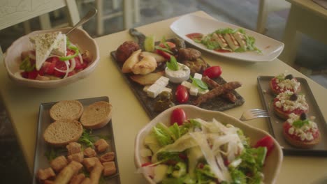 wide shot of assorted greek food on table including salads, cheese and bread