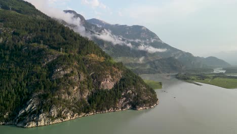 Aerial-view-up-Squamish-River-with-mountains-from-bay,-Squamish,-Canada