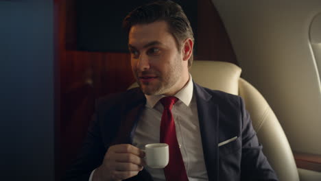 closeup luxury businessman traveling on private jet. happy man drinking coffee