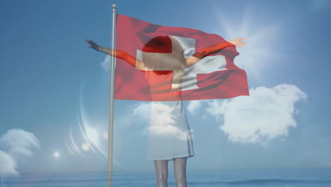 raising arms over swiss flag, person standing under cloudy sky background