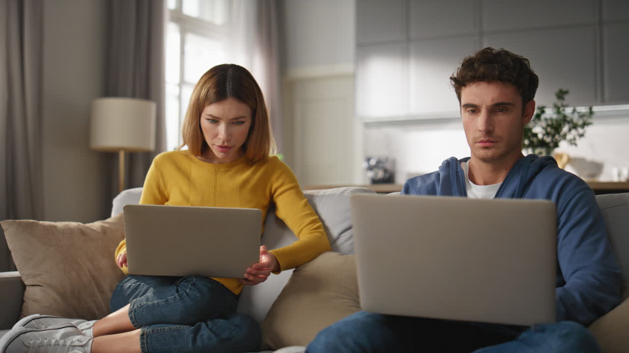 Focused spouses texting laptops sitting sofa together home closeup. Remote work
