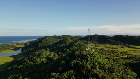 stunning aerial orbit of telecommunications satellite tower atop lush mountains and valley at tropical island catanduanes, philippines.