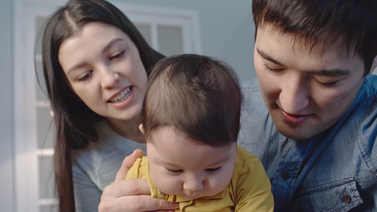 una pareja feliz sostiene a su pequeño bebé mientras hace una videollamada