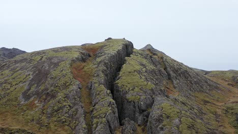 flying towards entrance of large crack in rocky hill of lambafellsgj?