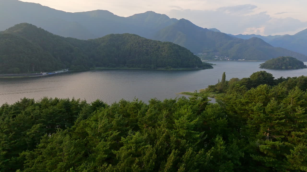 Drone rotating in front of forest with Lake Kawaguchi mountain background, Japan