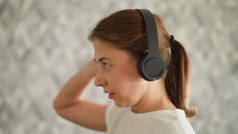 woman touches headphones while jogging closeup. sporty lady has blast with earpieces working out on treadmill in gym. combating tedium during exercise