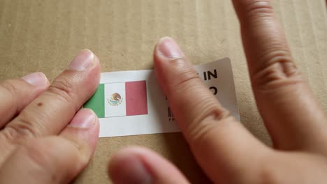 hands applying made in mexico flag label on a shipping box with product premium quality barcode