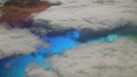 strange planet with multicolor sea water between white clouds seen from above