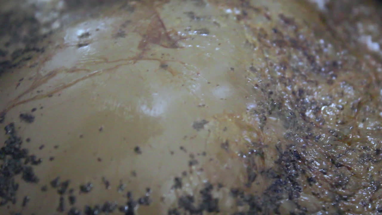 Tea boiling close up inside stainless steel pot, bubbles and spices moving on surface, hot beverage preparation, traditional chai texture, cooking process in home kitchen