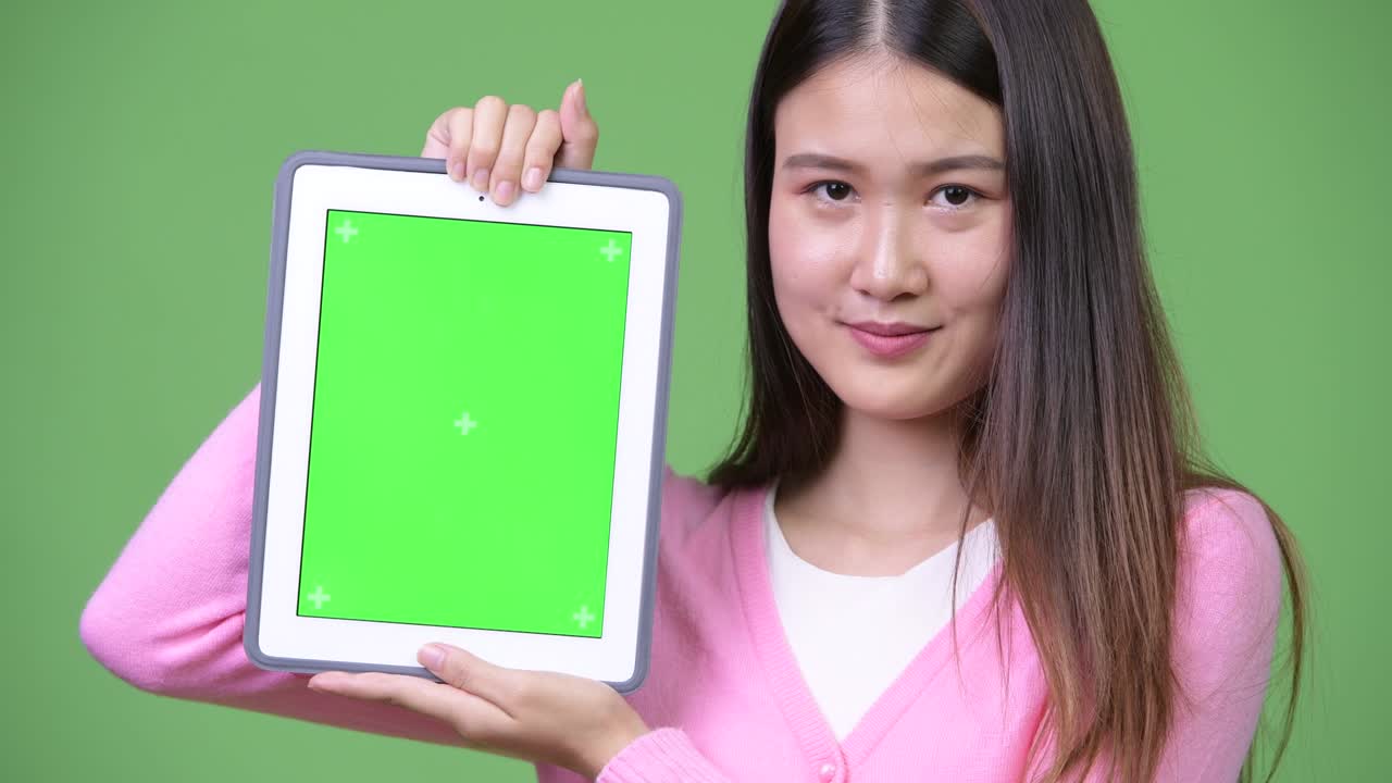 Young beautiful Asian woman showing digital tablet