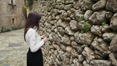 woman putting a piece of paper with a secret desire inside the old wall