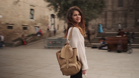 young woman with backpack in the middle of old big square