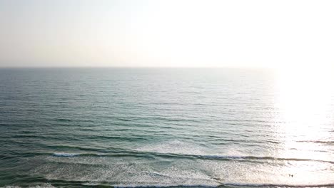 Sunlight-reflects-on-sea-surface-and-two-people-bathing-at-sunset