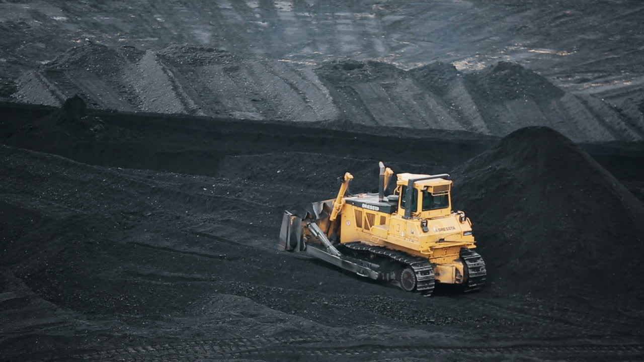 Bulldozer at coal warehouse. Tractor using for loading coal into trucks for further transport