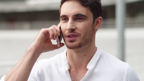 portrait of happy businessman having talk on mobile phone outside