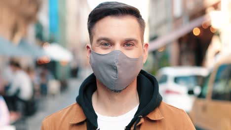 close-up view of caucasian man wearing mask looking at camera and smiling in the street