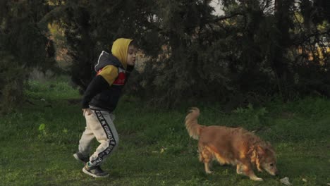 caucasian kid jumping around in the woods, playing with his pet dog, slow motion