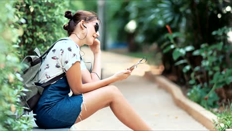 young beautiful woman listening to the music, dancing and singing in the park