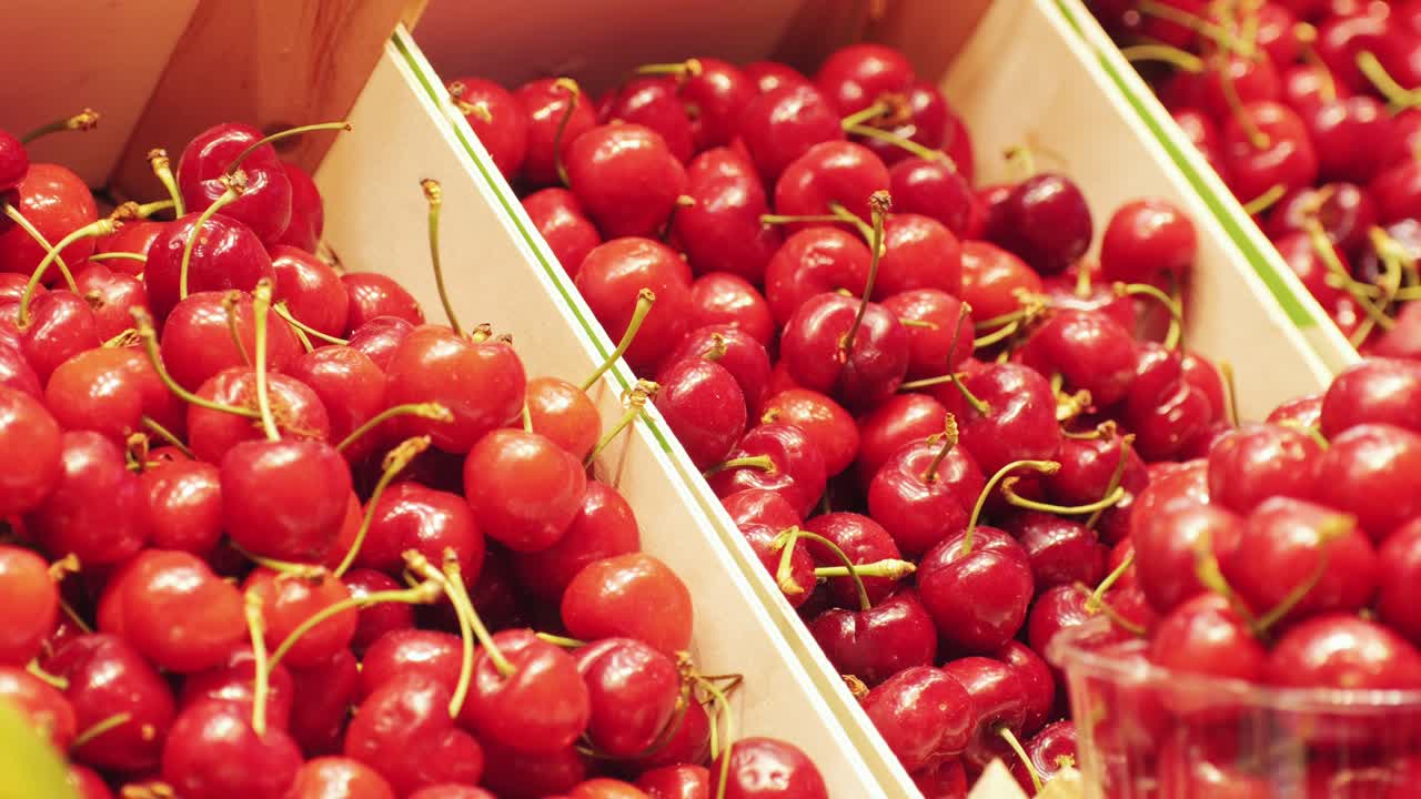 Ripe red cherries arranged attractively on a market stall, presenting an array of juicy and delicious fruits